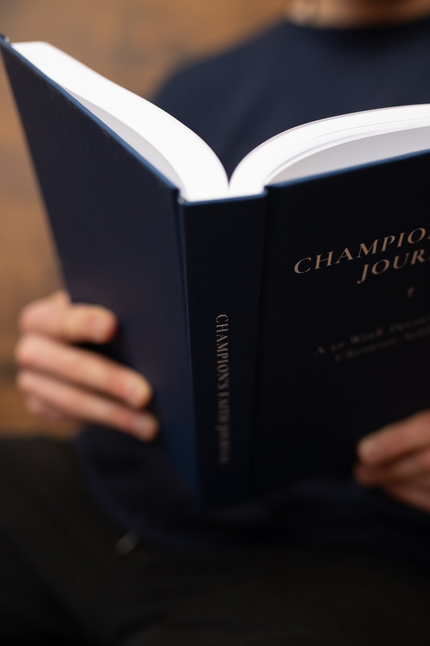 Person holding a blue book titled 'Champion' with a blurred background