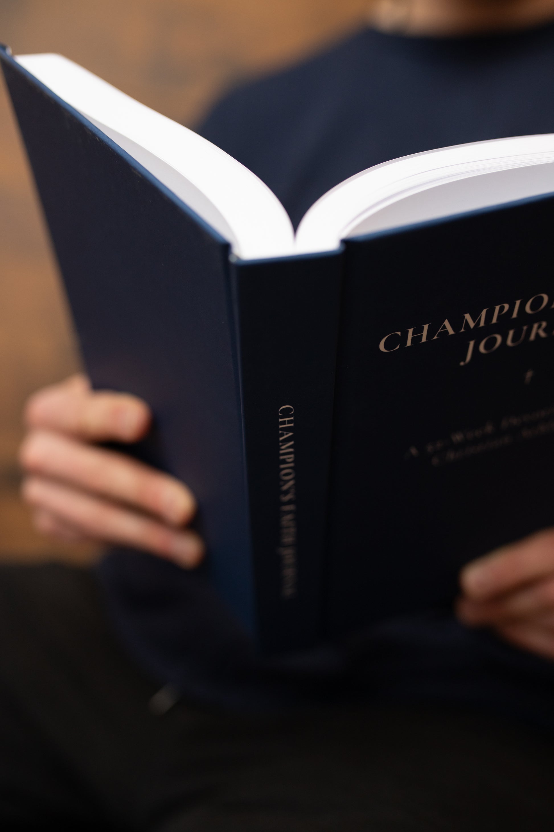 Person holding a blue book titled 'Champion' with a blurred background
